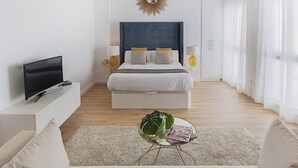 A modern hotel room with a large bed, a flat-screen TV, a bedside table with lamps, and a magazine on a glass coffee table. - iloftmalaga Císter Estudio (Málaga)