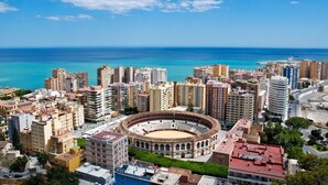 A cityscape with a prominent bullring surrounded by high-rise buildings and a clear blue sky. - iloftmalaga Císter Estudio (Málaga)
