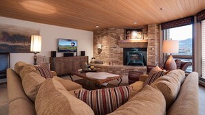 Ein gemütliches Wohnzimmer mit Kamin, Fernseher und einer bequemen Sitzecke.