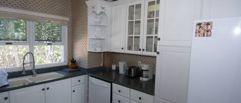 Una cucina con mobili bianchi, un lavello e una finestra.