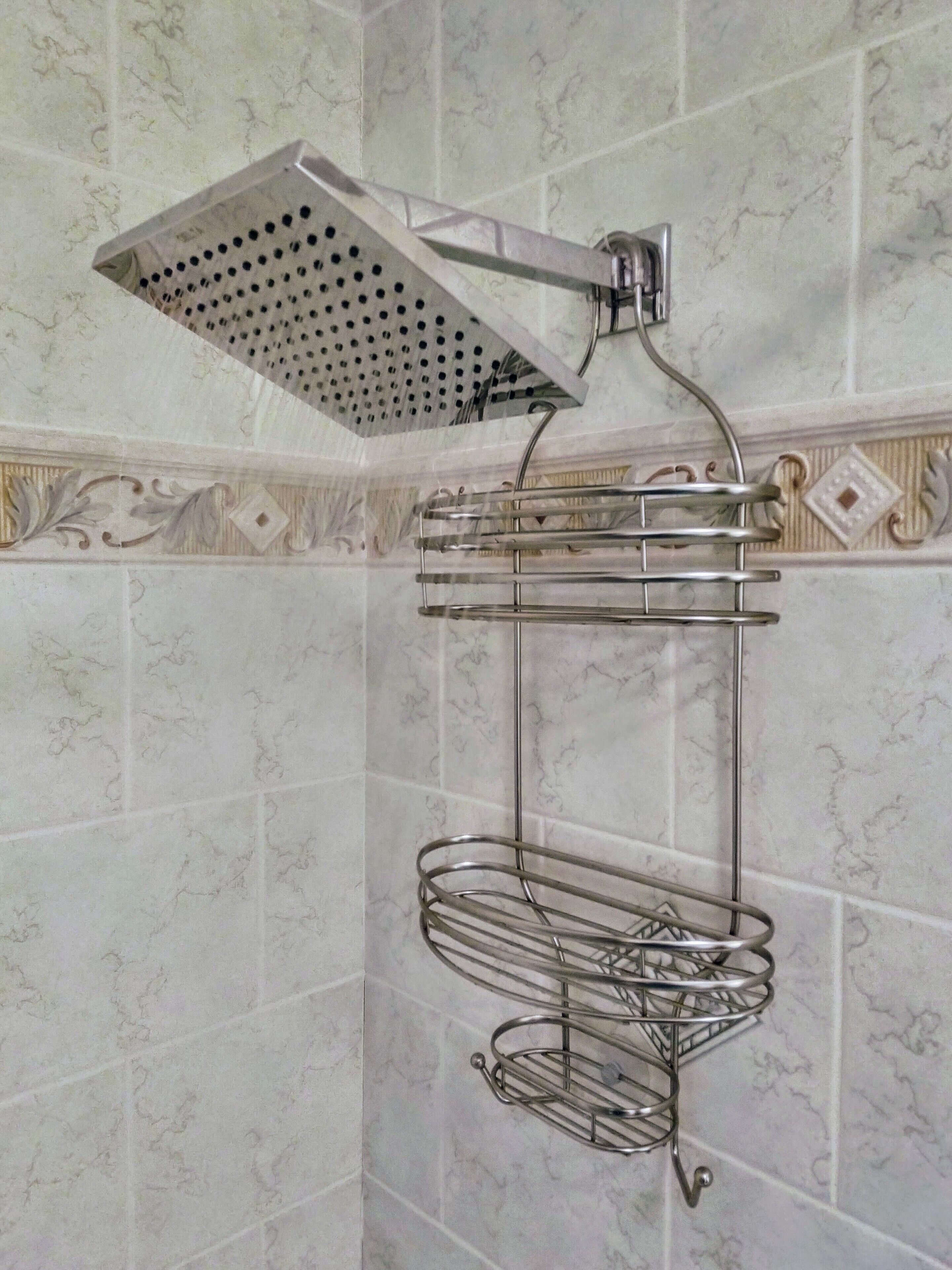 A bathroom with a shower head, a towel rack, and a towel holder.