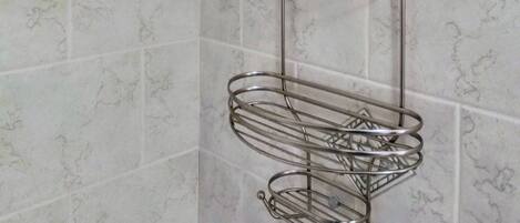 A bathroom with a shower head, a towel rack, and a towel holder.