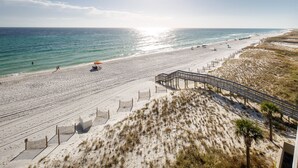 Ein Strand mit einer Holzpromenade, Sanddünen und freiem Blick auf den Ozean.