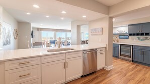 A modern kitchen with white cabinetry, stainless steel appliances, and a large island.