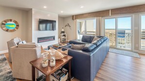 A modern living room with a fireplace, a large TV, and a balcony with a view of the city.