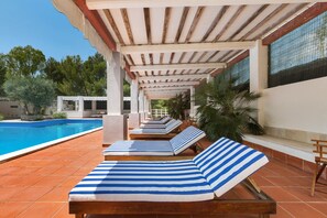 Ein Poolbereich mit Liegestühlen und einer Pergola.