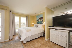 A hotel room with a bed, a TV, a dresser, and a painting on the wall. - Cozy Coastal Studio | Near Pool & Beach (Destin)