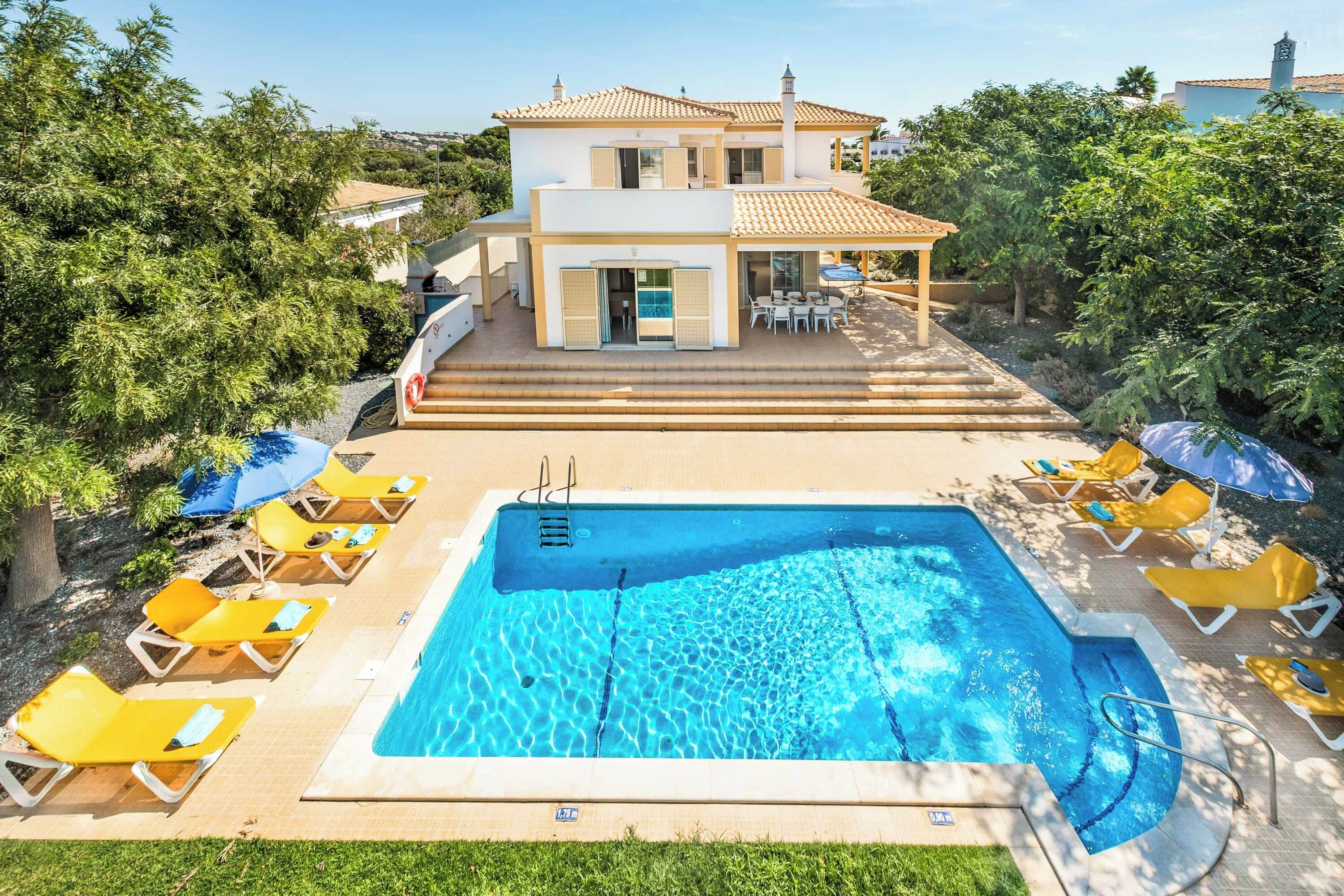 A two-story building with a swimming pool, sun loungers, and a covered patio area.