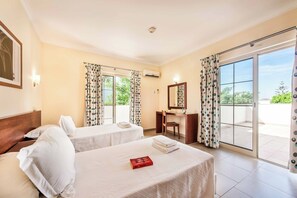 A hotel room with two beds, a desk, a chair, a mirror, and a sliding glass door to the outside. - Villa Altair - Four Bedroom Villa, Sleeps 8 (Casa Altair Joinal)