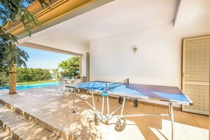 An outdoor ping pong table with wheels, a table and chairs, and a view of a swimming pool. - Villa Altair - Four Bedroom Villa, Sleeps 8 (Casa Altair Joinal)