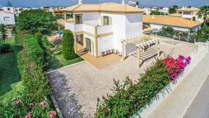 A two-story house with a tiled roof, a covered patio, and a garden with flowers. - Villa Altair - Four Bedroom Villa, Sleeps 8 (Casa Altair Joinal)