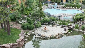 Un espace aménagé avec une piscine, un jacuzzi et un petit étang agrémenté d’un foyer extérieur.