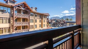 Un immeuble à plusieurs étages doté de balcons, de grandes fenêtres et offrant une vue sur les montagnes.