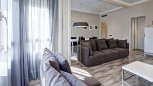 Una sala de estar moderna con un sofá, una mesa de centro y un comedor al fondo.