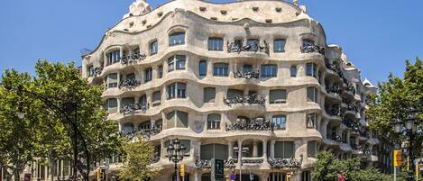 A multi-story building with unique architectural design, featuring balconies with sculptures, under a clear blue sky.