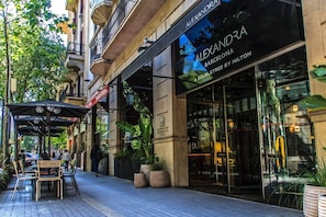 A hotel named 'ALEXANDRA BARCELONA' with a doubletree by Hilton, featuring outdoor seating and potted plants.