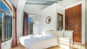 Un dormitorio con una cama grande, un aparador, un espejo y una puerta de madera.