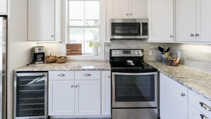 Une cuisine moderne avec des meubles blancs, une cuisinière en acier inoxydable, un four à micro-ondes et un four encastré.