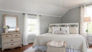 Une chambre à coucher avec un lit, une commode, une chaise et un miroir.