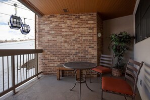 A balcony with a brick wall, a round metal table, two chairs, and a potted plant. - CX133 | Ski In/Out | Slopeside Convenience | Winter Shuttle | Amazing Views (Steamboat Springs)