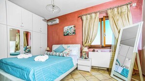 A bedroom with a bed, a nightstand, a mirror, and a window with curtains.