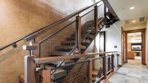 Una scala in legno a più livelli con ringhiere in metallo e un muro in pietra.