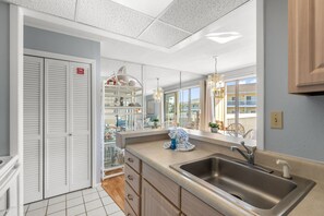 A modern kitchen with a large window, a sink, and a dining area with chairs.