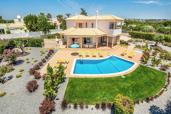 Ein zweigeschossiges Haus mit Swimmingpool, Sitzgelegenheiten im Freien und einem gepflegten Garten.