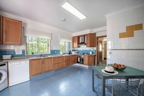 A modern kitchen with wooden cabinets, a dishwasher, a stove, and a dining area with a table and chairs.