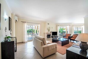 Ein Wohnzimmer mit einer Couch, einem Couchtisch, einem Fernseher und einem Kamin.
