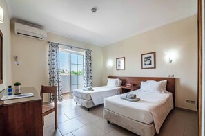 Ein Hotelzimmer mit zwei Betten, einem Schreibtisch, einem Stuhl und Blick ins Freie.