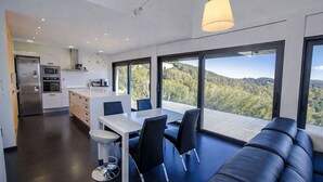 Eine moderne Küche mit Essbereich, große Fenster mit Blick auf die Hügel und eine gemütliche Sitzecke.
