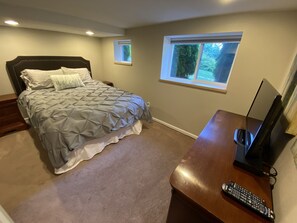 Une chambre avec un lit, un bureau, une télévision et une fenêtre.