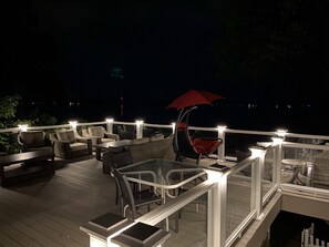 Une terrasse extérieure avec des meubles en osier, une table en verre et un parasol rouge.
