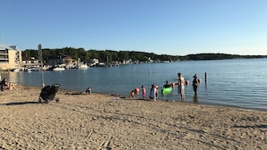 A sandy beach with boats in the water and buildings in the background.