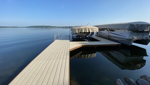 A wooden dock extending into calm water with boats docked on the right.
