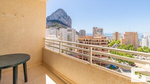 Een balkon met uitzicht op een rotsachtige berg en stadsgebouwen.