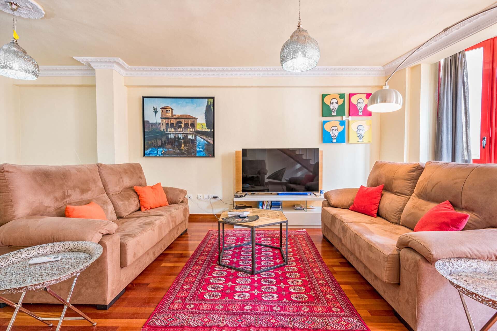 Una sala de estar con dos sofás, una mesa de centro, un televisor y una alfombra roja estampada.