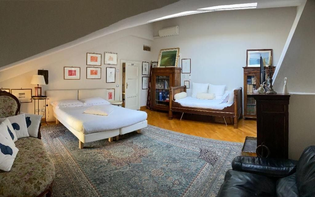 Un dormitorio con dos camas, un sofá, una silla y un armario de madera.