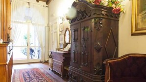 A traditional room with a wooden cabinet, a patterned rug, and a large mirror. - A La Maison Ravenna (Ravenna)
