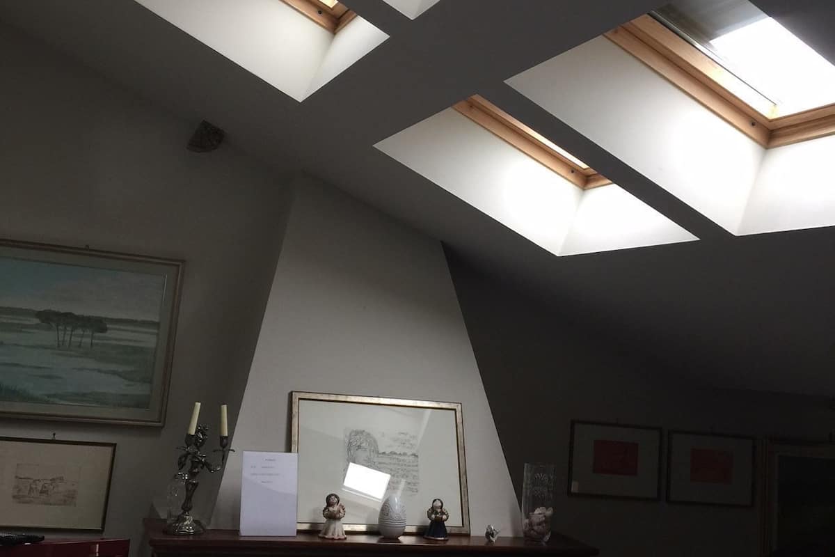 A room with skylights, a fireplace, and framed artwork on the walls.