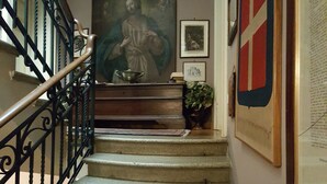 A staircase with a metal railing, a painting above, and a framed document on the wall. - A La Maison Ravenna (Ravenna)