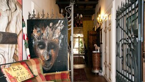 A hallway with a checkered sofa, a painting, and a wrought iron gate. - A La Maison Ravenna (Ravenna)