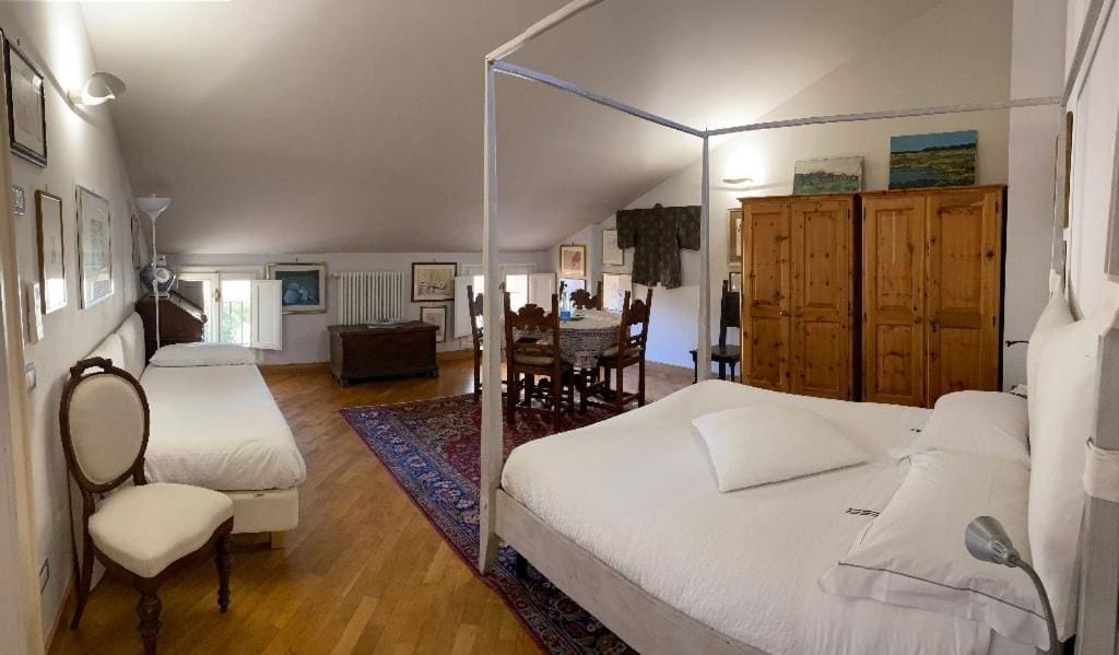 Quarto com cama de dossel, área de estar com mesa e cadeiras, e armários de madeira.
