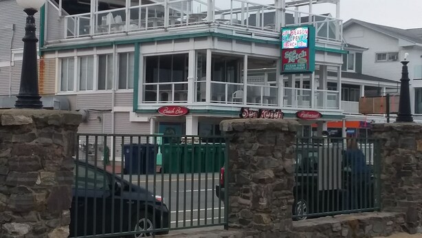 A multi-story building with a green and white color scheme, featuring a sign for 'Sea Ketch' and 'Beach Club'. - Central AC, child safe fenced in yard, 3 minutes to the beach.  NO CLEANING FEE
 (Hampton)