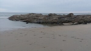 A sandy beach with large rocks in the water and footprints in the sand. - Central AC, child safe fenced in yard, 3 minutes to the beach.  NO CLEANING FEE
 (Hampton)