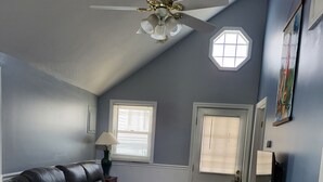 A living room with a leather sofa, a dining table with chairs, a ceiling fan, and a small table with electronic devices. - Central AC, child safe fenced in yard, 3 minutes to the beach.  NO CLEANING FEE
 (Hampton)