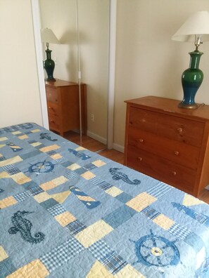 A bedroom with a bed, a wooden dresser, a mirror, and a green lamp. - Central AC, child safe fenced in yard, 3 minutes to the beach. NO CLEANING FEE
(Hampton)
