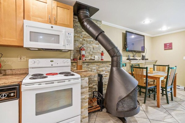 Kitchen, Dining & Fireplace - The open-concept layout keeps everyone connected, with a fully equipped kitchen, dining space, and distinctive fireplace creating a warm and inviting gathering place.