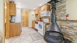 A kitchen with wooden cabinets, a microwave, a stove, and a wood-burning stove.
